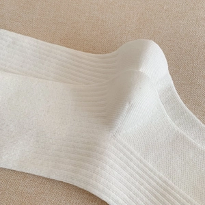 Gros plan de chaussettes en coton blanc tricoté montrant la texture côtelée douce