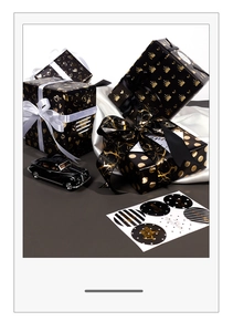 Detail showing black and gold gift wrapping paper with hearts, crowns and ribbons