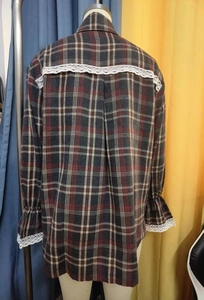 Detail of red and grey plaid shirt with white lace patchwork on the back and cuffs