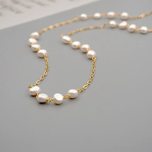 Layered baroque freshwater pearl necklace with thin gold chain in a minimalist design