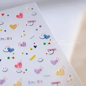 Vue macro détaillée de stickers nail art 5D gaufrés avec cœurs colorés et sourires