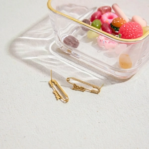 Détail de boucles d'oreilles trombones dorées avec lettrage love et cool et strass