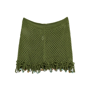 Close-up of green knit bohemian skirt featuring hollow crochet and colorful beaded tassels