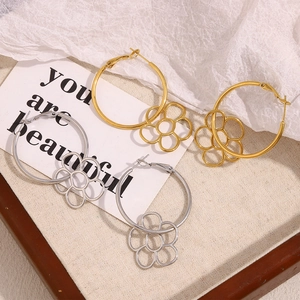 Gros plan de boucles d'oreilles avec pendentif fleur en or et argent sur fond artistique