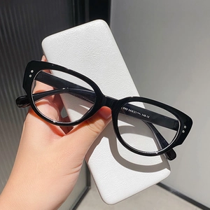 Detail of black cat-eye sunglasses with rice-shaped studs and white leather case