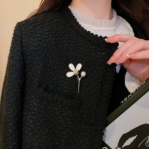 Détail d'une broche fleur avec perles et zircon sur un revers de veste en tweed