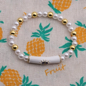Macro detail of evil eye bead bracelet with pearls, gold beads and rhinestone accents