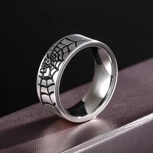 Close-up of a silver 316L stainless steel ring with a black spider web pattern on a jewelry box