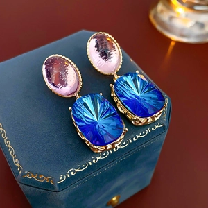 Close-up of vintage earrings with pink oval and dark blue rectangular gemstones