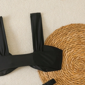Détail du haut de bikini noir avec design plissé et tissu extensible de haute qualité