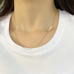 Close-up of minimalist gold cross choker necklace on model wearing white t-shirt
