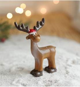 Gros plan d'une mini figurine de renne en résine avec bonnet rouge sur fond de neige