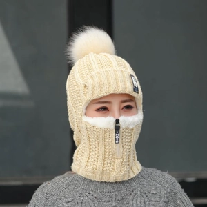 Détail de la cagoule en tricot crème avec fermeture éclair et gros pompon en fourrure
