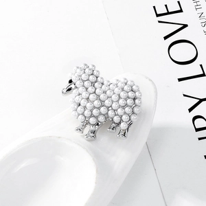 Détail macro d'une broche mouton en argent avec métal poli et perles blanches incrustées
