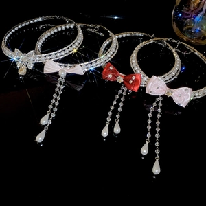 Macro shot of layered faux pearl choker with rhinestone bow and tassel pendant details
