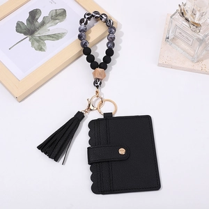 Detail of black leather card holder with marble silicone beaded wristlet and tassel keychain