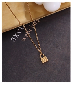 Close-up of a minimalist 18k gold-plated lock pendant on a fine titanium steel chain