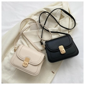 Close-up of stylish contrast lock on black and cream leather crossbody flap bags