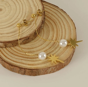Detailed shot of golden star and pearl tassel earrings on rustic wooden displays