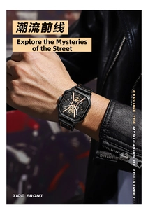 Detail view of square black watch with skeleton dial and orange stitching on leather strap