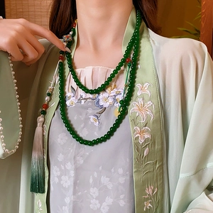 Detail view of a green beaded double-layer necklace with elegant tassels and vintage floral design
