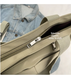 Detail of smooth metal zipper and durable khaki canvas handle on a stylish tote bag