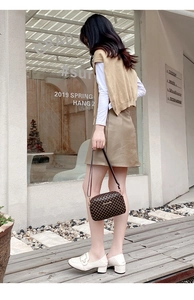 Detail of dark brown checkered crossbody square bag with golden hardware and chain strap