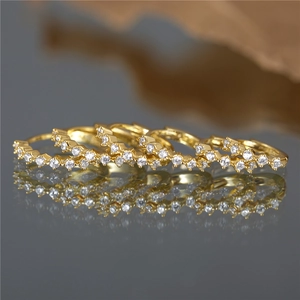 Macro shot of gold-plated hoop earrings with micro-set zircons and a mirror reflection