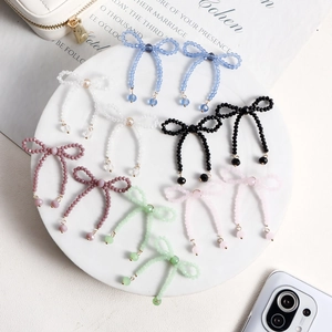 Detailed view of handmade beaded bow earrings in six colors displayed on a white ceramic tray