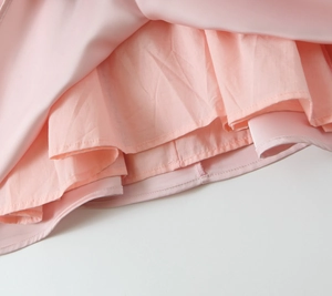 Détail de l'ourlet multicouche et des coutures sur une mini robe rose