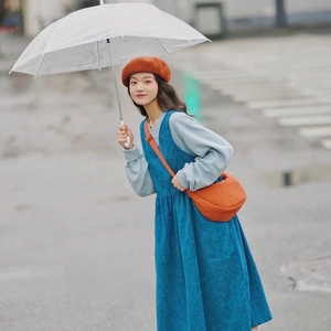 Nylon dumpling crossbody bag in bright orange styled with a blue corduroy dress