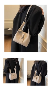 Detail of beige bucket bag with litchi grain texture and elegant leather strap buckle