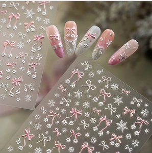 Close-up of 5D pink bow and white snowflake embossed nail stickers with winter aesthetic