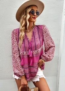 Close-up of pink Bohemian blouse featuring V-neckline with tassel ties and floral print