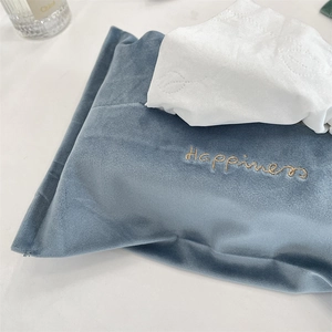 Detail of blue velvet tissue bag with golden Happiness embroidery in a home setting