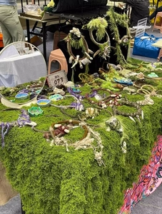 Detailed close-up of artificial moss jewelry and crystal pendants on a textured display