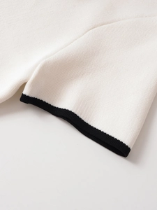 Close-up of white knit fabric with premium black contrast trim on the sleeve edge