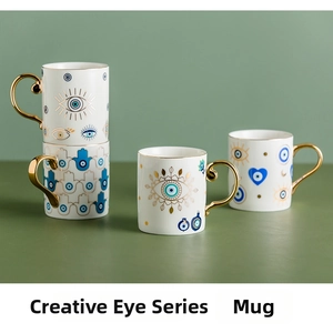 Detail of Nordic ceramic mugs featuring gold-rimmed Evil Eye and Hamsa Hand patterns