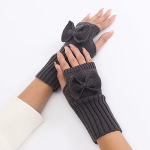 Detail of dark grey knitted fingerless gloves with 3D bow accent and ribbed cuff