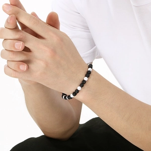 Men's beaded bracelet featuring black lava rock and white turquoise stones on a wrist