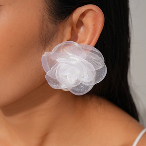 Gros plan d'une grande boucle d'oreille fleur en tissu blanc portée par un mannequin de profil