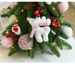 Close-up of Nordic mini Christmas tree with felt animals, pine cones and warm LED lights
