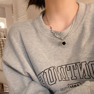 Detail of a layered silver necklace with a black heart pendant and star accents on model