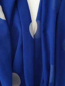 Vue détaillée du tissu en mousseline à pois bleus montrant la texture du col écharpe