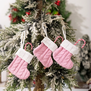 Close-up of three pink cable-knit mini Christmas stockings with white cuffs and hanging loops