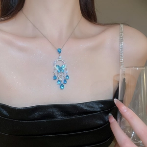 Detail of silver butterfly tassel necklace with blue cubic zirconia on model neck