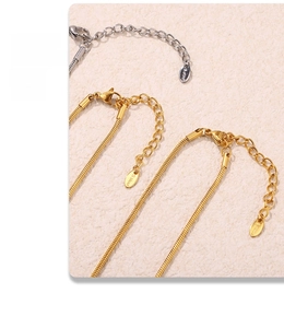 Detail of snake head necklace with lobster clasp and S.Steel tag on beige texture