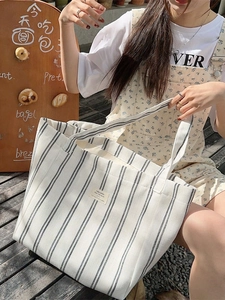 Large striped canvas tote bag with black vertical lines and broad shoulder straps