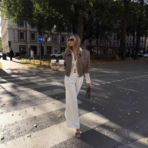Outfit chic da donna con giacca marrone avvitata, camicia in pizzo e pantaloni bianchi larghi