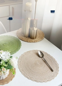 Detail of hand-woven round cotton placemats with spiral braid and wavy edge on table